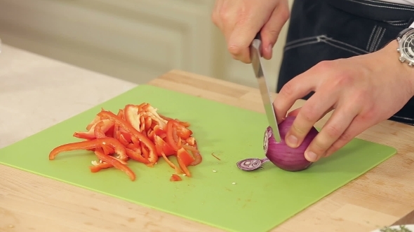 Cheff Is Slicing Red Onion On a Cutting Board