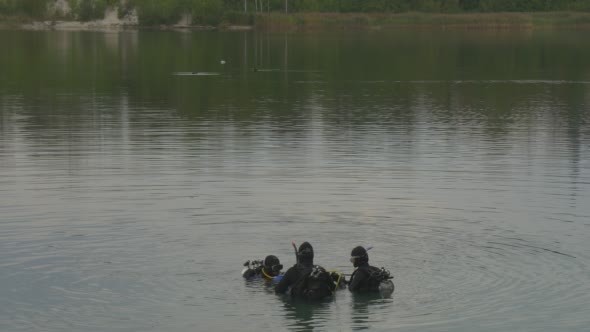 Three Divers Distantly Are Standing in The Water