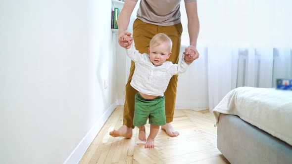 Baby Making First Steps and Daddy Helping Him