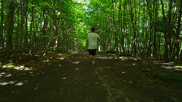 Young Man In Sportswear Running Amidst Trees