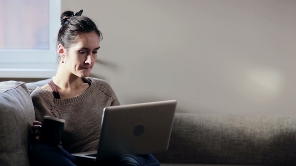 Woman Sitting In Sofa And Working On Laptop