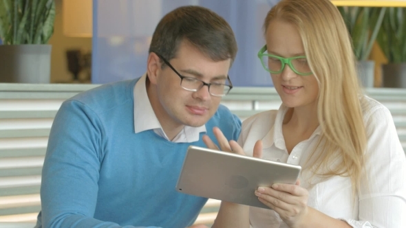 Man And Woman Spending Time With Tablet PC In Cafe