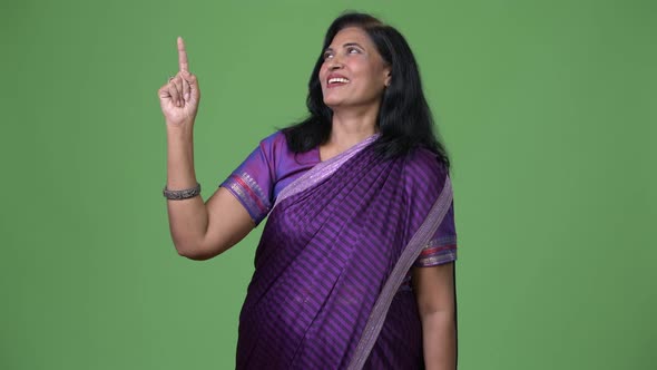 Mature Happy Beautiful Indian Woman Pointing Up While Thinking