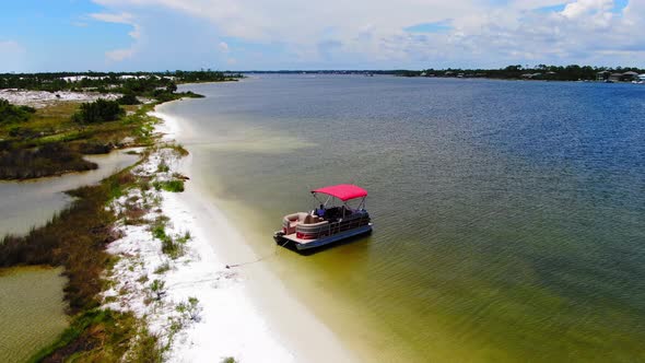 Aerial view panning away of a pontoon boat on some small islands near Destin Florida.