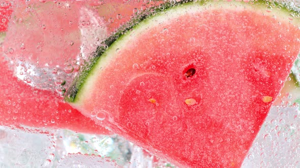 Super Slow Motion Shot of Bubbling Water with Melon Slices and Ice Cubes in Glass at 1000 Fps