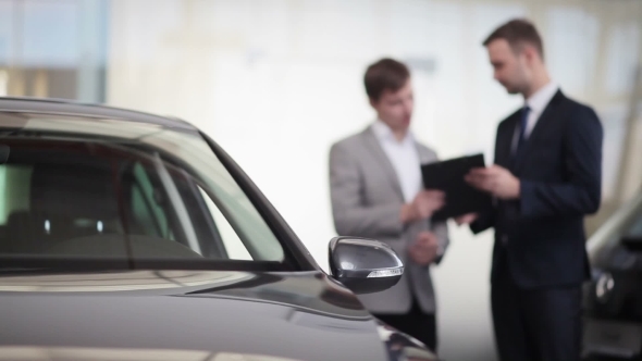 Sales Manager Assisting Client In a Car Dealership alt