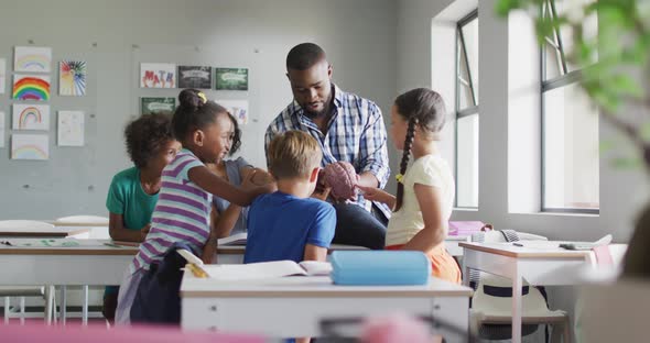 Video of happy african american male teacher and class of diverse pupils during biology lesson