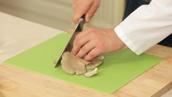 Chef Is Slicing Brown Mushrooms On a Cutting Board