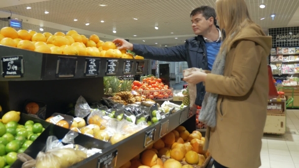 Happy Couple Choosing Oranges In Supermarket