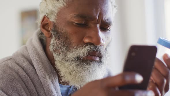 Senior man using smartphone while holding empty medication container