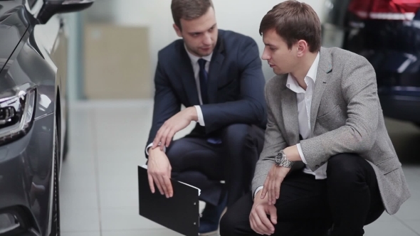 Young Man Examining Wheels Of The Car alt