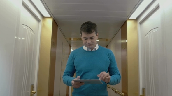 Man Working With Pad In Hotel Hallway