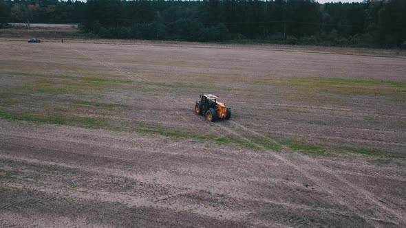 A Yellow Excavator Moving Across The Field On A Sunny Day - Tracking Shot