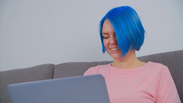 Student girl with blue colored hair studying online with portable computer and internet