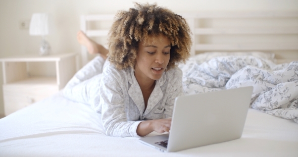 Woman Looking At Laptop In Bed At Home