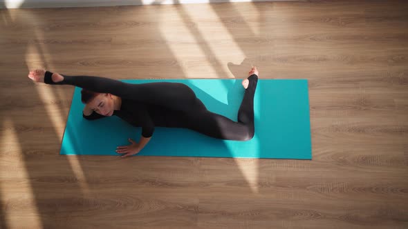 Woman Doing Yoga and Stretching While Lying on a Fitness Mat at Home
