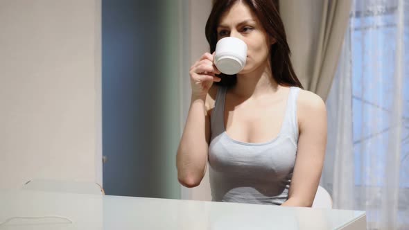 Young Woman Drinking Hot Coffee Sitting at Home