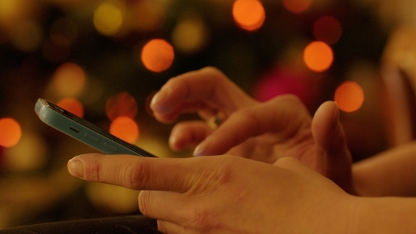 Woman Hands With Smartphone By Christmas Tree alt