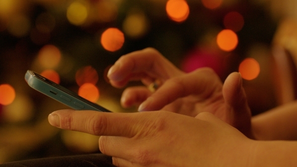 Woman Hands With Smartphone By Christmas Tree