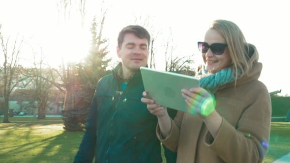 Man And Woman Walking And Using Tablet PC