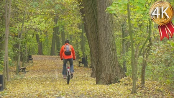 Man in Orange Jacket And Safety Bicycle Helmet