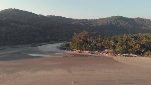 Footage of a beach, at sunset, during a low tide at the tourist destination spot of Palolem, India