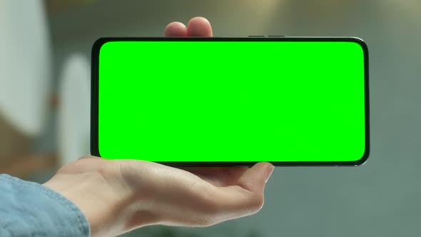 Young Woman at Home Holding Chroma Key Green Screen Smartphone Watching Content Without Touching or