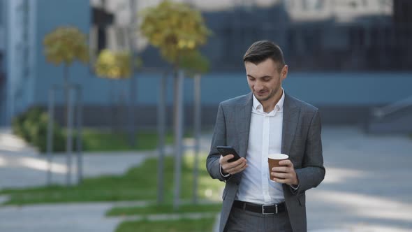 Bearded Businessman Using Mobile Phone While Walking Near Business Center