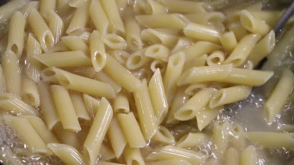 Mixing Cooked Soft Penne Pasta in Bowl