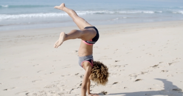 Young Woman Doing Cartwheel On Beach