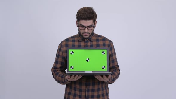 Happy Young Indian Hipster Man Showing Laptop and Looking Surprised