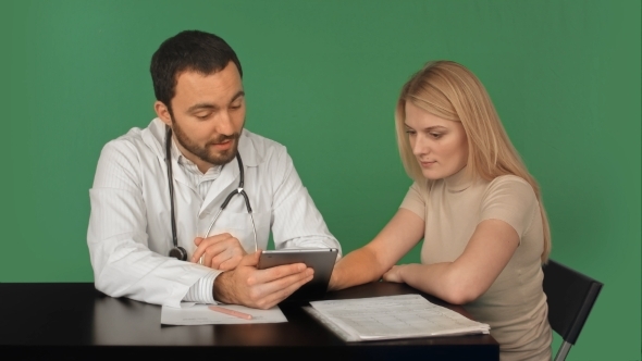 Doctor Using Digital Tablet Talking With Patient