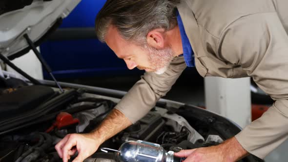 Mechanic checking car engine oil and showing thumbs up