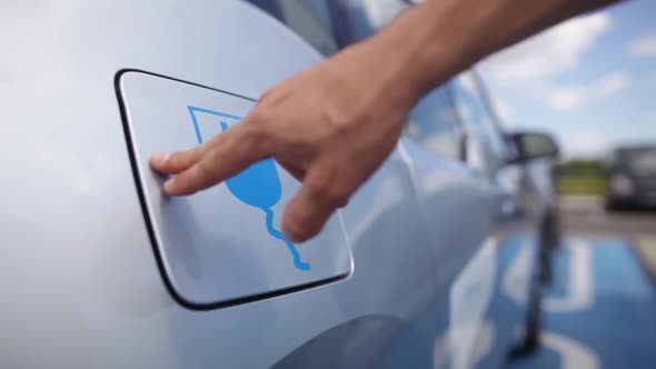 Hand opening the lid of an electrical car, for charging