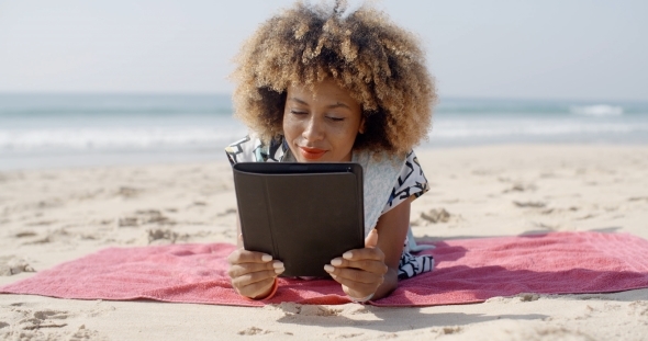 Woman Uses A Tablet On The Beach alt