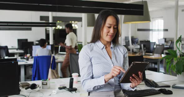 Focused asian businesswoman working on tablet in office