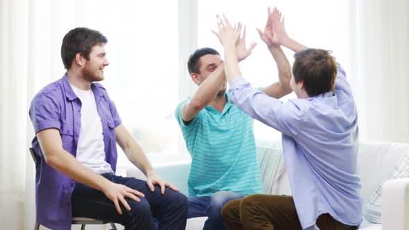 Smiling Male Friends Giving High Five At Home