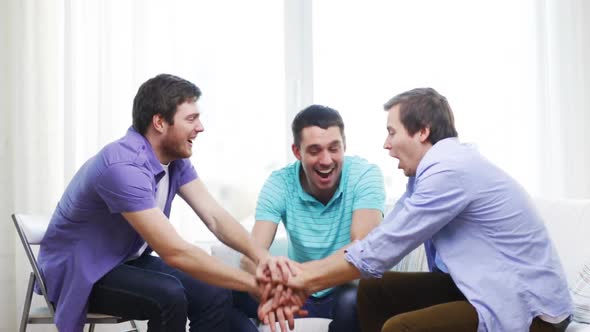 Smiling Male Friends With Hands Together At Home