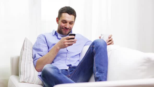 Smiling Man With Smartphone And A Cup At Home