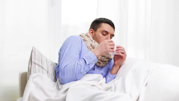 Ill Man With Flu At Home Sneezing And Blowing Nose 2