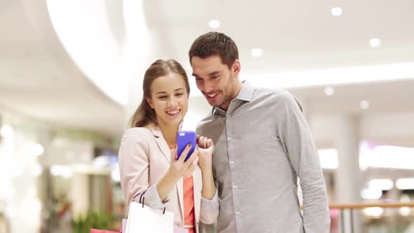 Couple With Smartphone And Shopping Bags In Mall 3