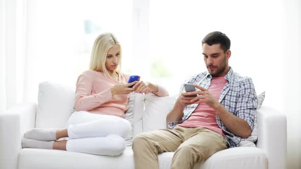 Couple With Smartphones Texting At Home 6