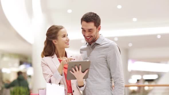 Couple With Tablet Pc And Shopping Bags In Mall 4