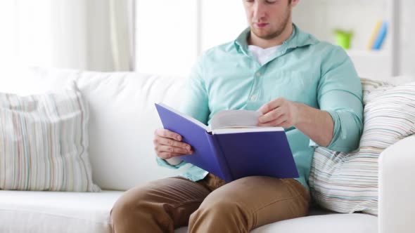 Man Reading Book And Sitting On Couch At Home