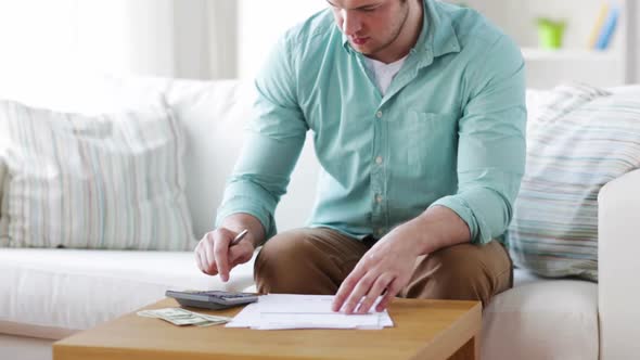 Man With Calculator, Papers And Money At Home