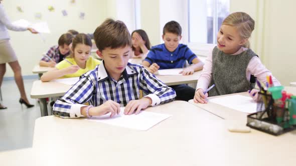 Group Of School Kids Writing Test In Classroom 3