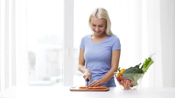 Smiling Young Woman Chopping Vegetables At Home