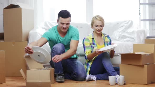 Smiling Couple Unpacking Boxes With Kitchenware 1
