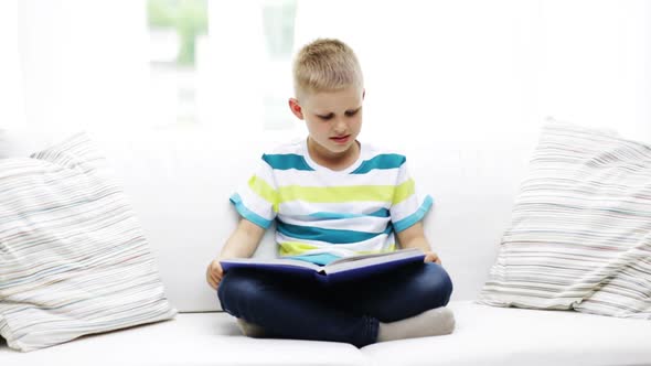 Smiling Little Schoolboy Reading Book At Home 1