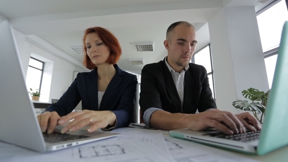 Businesswoman And Businessman In Suits Sitting